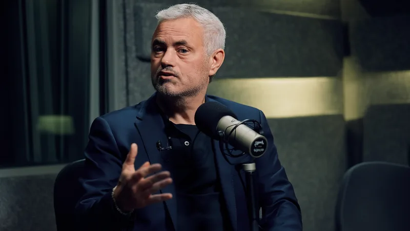 José Mourinho con gesto serio durante una rueda de prensa, vistiendo traje oscuro y camisa blanca, con micrófonos y periodistas al fondo.
