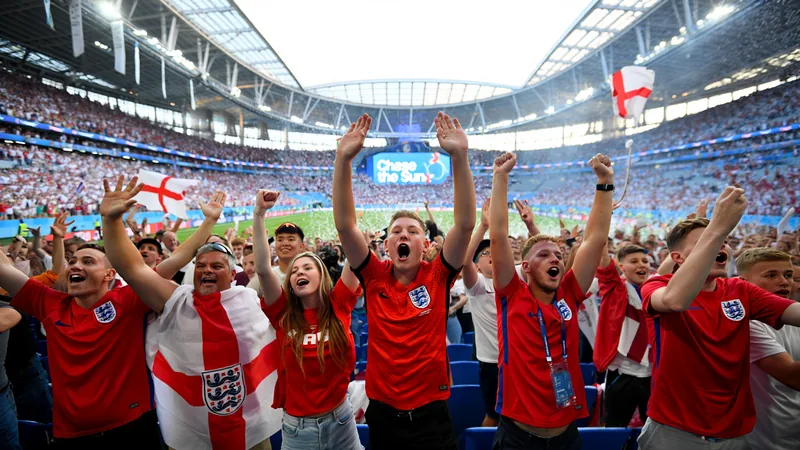 ¿Por qué Inglaterra usa una canción de dardos en el Mundial Aficionados ingleses celebrando un gol en un estadio del Mundial 2026 con banderas de Inglaterra y una pantalla mostrando el marcador.