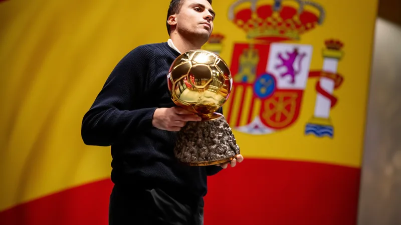 Rodri con el Balón de Oro en una mano y la camiseta de la selección española en la otra, sonriendo en una sala de conferencias con el logo del