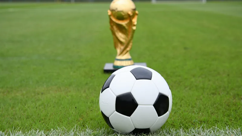 ¿Tres puntos bastarán para avanzar en el Mundial? — Football World Estadio de fútbol lleno con aficionados ondeando banderas durante un partido del Mundial, con el marcador mostrando 1-1 en la fase de grupos.
