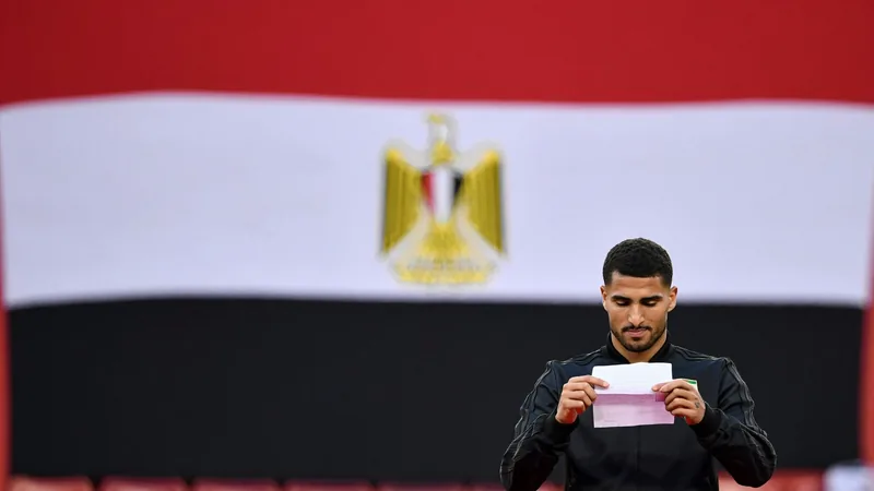 Carta emotiva a Emam Ashour antes del Mundial — Football World Cup Emam Ashour, centrocampista egipcio, sosteniendo una carta con emoción, con el logo de la Copa Mundial de la FIFA al fondo