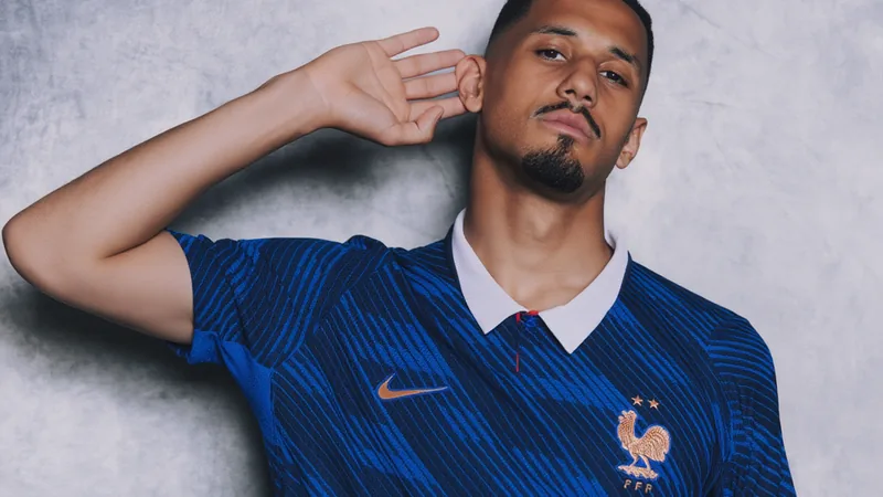 William Saliba regresa a los entrenamientos de Francia — Football William Saliba con la camiseta de la selección francesa entrenando en el campo de fútbol, sonriendo y mirando a la cámara.