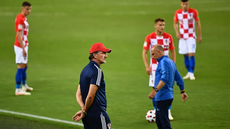 Dalic deja de ser seleccionador de Croacia tras nueve años — Football Zlatko Dalic, seleccionador de Croacia, con gesto serio durante un partido del Mundial, vistiendo traje y corbata, con la bandera croata al fondo.
