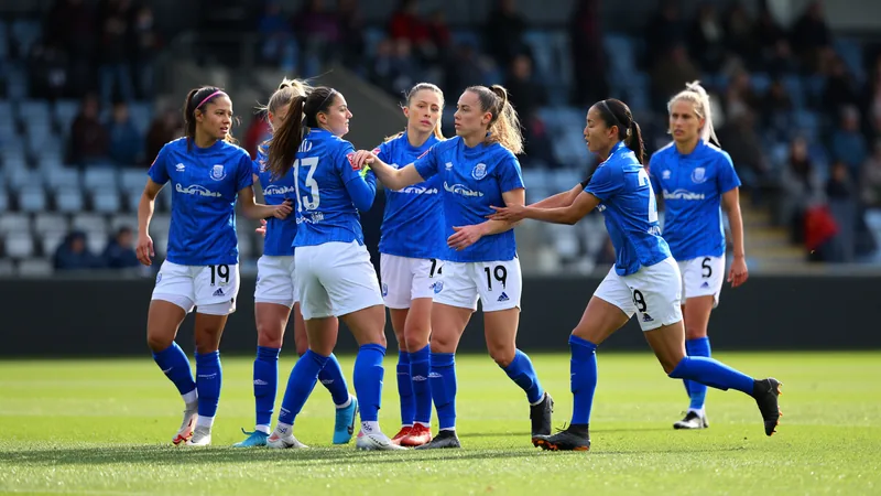 Una jugadora de fútbol femenino con la camiseta de Inglaterra mirando el campo, con un estadio de fondo y banderas de la FIFA ondeando.