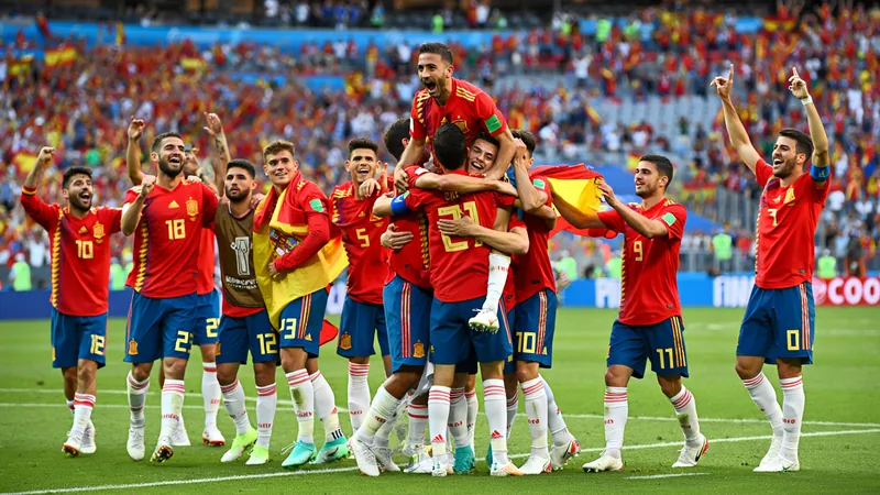 España avanza a semifinales del Mundial: se enfrentará a Francia Jugadores de la selección española celebrando la victoria sobre Bélgica en el campo de juego, con el marcador de fondo y aficionados animando.