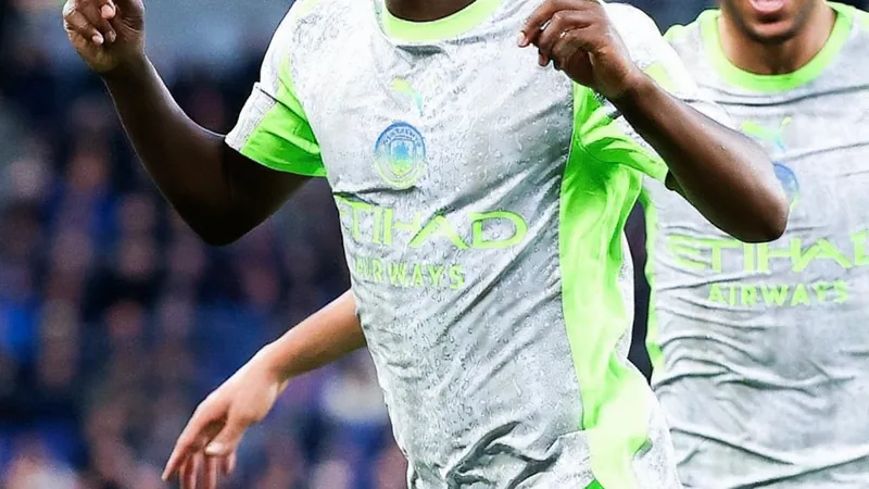 Jeremy Doku con la camiseta del Manchester City celebrando un gol en el Etihad Stadium, con aficionados de fondo — latest news and analysis.