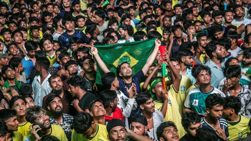 Aficionados brasileños con la camiseta amarilla celebrando en un estadio lleno de banderas y confeti durante un partido de la Copa Mundial.