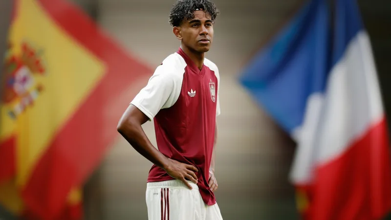 Lamine Yamal: “Francia tiene dos opciones… o llegar a tres finales Lamine Yamal, jugador del FC Barcelona, sonriendo con la camiseta de la selección española en un campo de fútbol, con el estadio de fondo.
