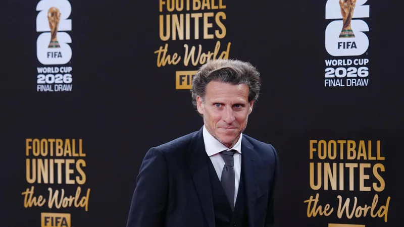 Diego Forlán con traje y sonrisa en una rueda de prensa, con el escudo de la selección uruguaya de fondo en Montevideo. — latest news and analysis.