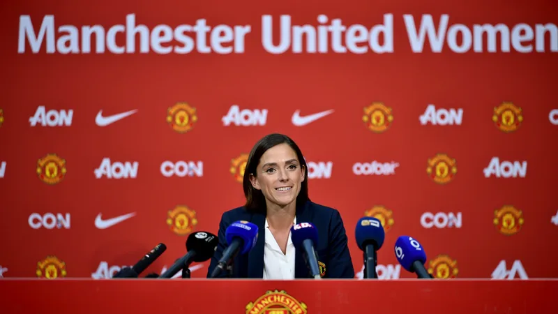 Eva Olid, nueva entrenadora del United femenino — Football World Cup Eva Olid sonriendo con una bufanda del Manchester United en el estadio Old Trafford, con el césped y las gradas de fondo.