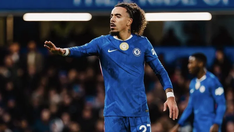 Malo Gusto con la camiseta del Chelsea durante un partido en Stamford Bridge, con el balón en los pies y aficionados de fondo.