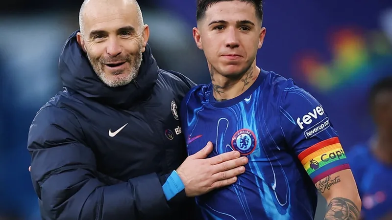 Enzo Fernández con la camiseta del Chelsea celebrando un gol en un estadio lleno, con el logo del Manchester City de fondo en una pantalla gigante.