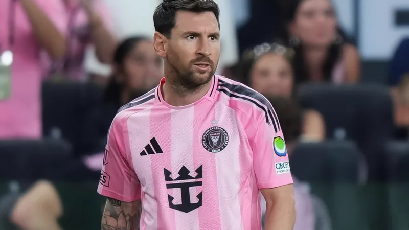 Lionel Messi con la camiseta del Inter Miami saliendo al campo en un estadio lleno, con gesto serio y brazalete negro en memoria de su padre.