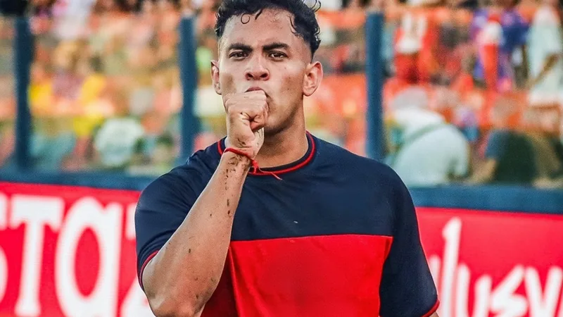 David Romero, delantero argentino, con la camiseta de Tigre, celebrando un gol en un estadio, con aficionados de fondo. — latest news and analysis.