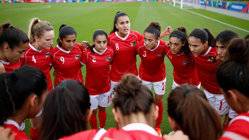 Jugadoras del equipo femenino afgano Afghan Women United abrazadas en el vestuario antes de un partido en Auckland, Nueva Zelanda, con bandera afgana