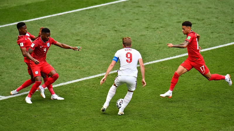 Analyse tactique : l'Angleterre séduit mais doit resserrer sa défense Joueurs anglais en maillot blanc célébrant un but lors d'un match de Coupe du monde, avec un stade rempli de supporters en arrière-plan.