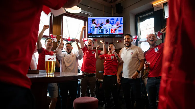 Supporters anglais en liesse dans un pub de Londres, drapeaux anglais agités, célébrant la victoire 4-2 contre la Croatie en Coupe du Monde.
