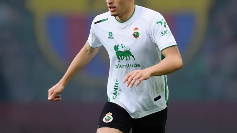 Barcelone cible Jorge Salinas, clause de 8 M€ activable — Football Un jeune défenseur central en action lors d'un match de football, portant le maillot du Racing Santander, sur fond de pelouse verte.