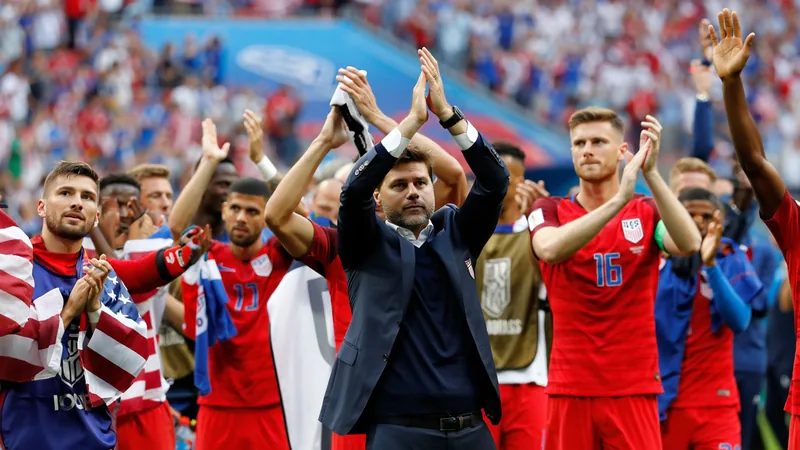 Mauricio Pochettino célébrant une victoire avec les joueurs américains sur la pelouse d'un stade, sous les acclamations des supporters.