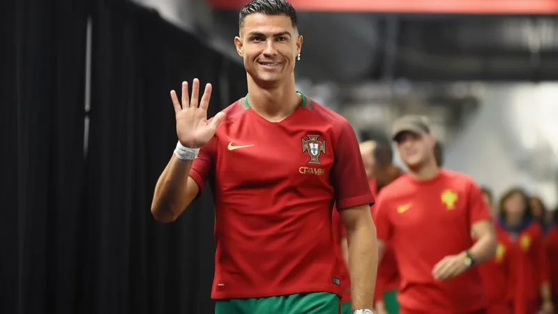 Cristiano Ronaldo en tenue du Portugal, célébrant un but, avec le maillot rouge et le numéro 7, devant des supporters en liesse.