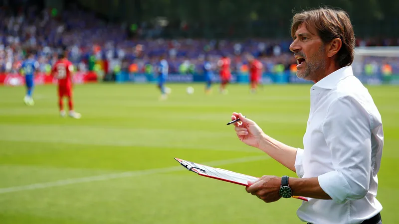 Hervé Renard peut-il relancer la campagne du Mondial de la Tunisie Hervé Renard en costume blanc sur le bord du terrain, regardant le match avec une expression déterminée, drapeau tunisien en arrière-plan.