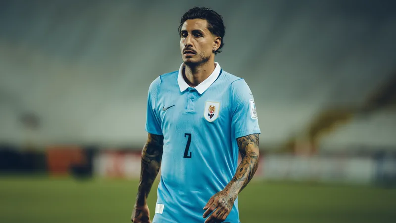 José María Giménez en tenue de l'Uruguay, concentré sur le terrain, avec le maillot celeste et le brassard de capitaine, lors d'un match de football.