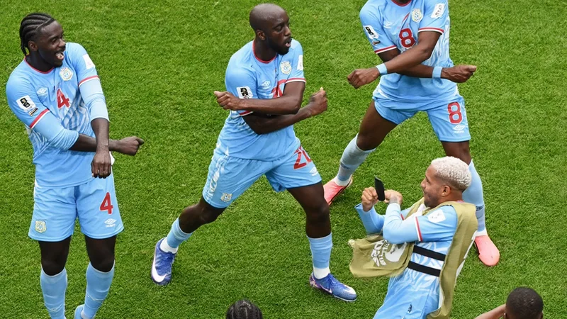 Joueurs de football de différentes nations s'entraînant dans une académie moderne en Europe de l'Ouest, avec des drapeaux en arrière-plan.