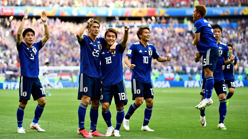 Joueurs japonais célébrant une victoire lors d'un match de Coupe du monde, avec le drapeau du Japon agité par les supporters en arrière-plan.