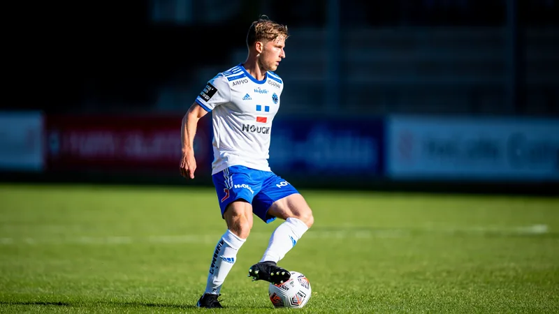 Un jeune joueur de football norvégien en tenue de Wigan Athletic, souriant, sur un terrain vert, avec un violoncelle en arrière-plan symbolisant