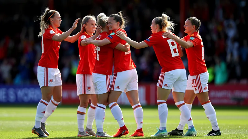 Joueuses galloises sans club : vitrine réussie — Football World Cup Joueuses galloises en action sur un terrain de football, portant le maillot rouge du pays de Galles, célébrant un but lors d'un match de