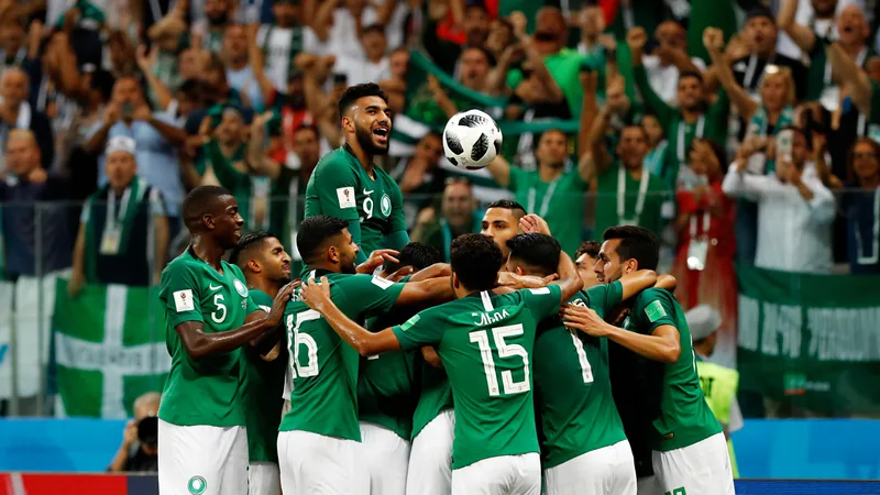 Les milliards de la Saudi Pro League profitent-ils à l'équipe Joueurs de l'équipe d'Arabie saoudite célébrant un but en maillot vert lors d'un match de Coupe du monde, avec le stade en arrière-plan.