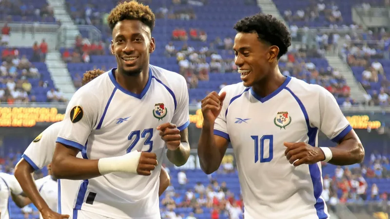 Les sept double-participants panaméens à la Coupe du Monde — Football Sept joueurs de l'équipe du Panama posant ensemble sur un terrain de football, portant leur maillot rouge, souriant devant un drapeau panaméen.