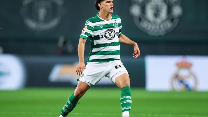 Manchester United toujours en course pour Mateus Fernandes, prix fixé Un jeune joueur de football en tenue du Sporting CP, souriant, sur un terrain vert avec des supporters en arrière-plan flou.