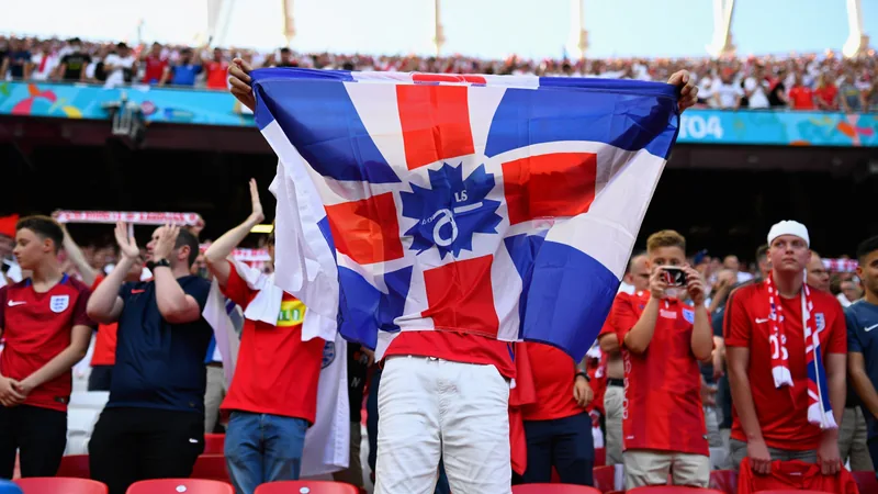 Mon drapeau anglais est devenu viral à l'Euro 2024 — Football World Un supporter anglais brandissant un drapeau humoristique dans un stade allemand lors de l'Euro 2024, avec des caméras de télévision braquées sur lui.