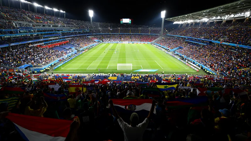Pourquoi une Coupe du monde surdimensionnée et politisée a un coût Vue aérienne d'un stade de football moderne avec des grues et des chantiers de construction en arrière-plan, symbolisant l'expansion du tournoi.