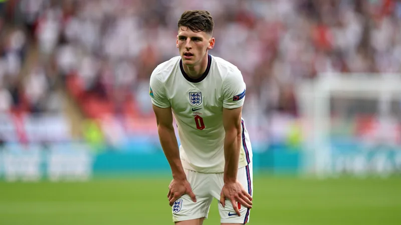 Rice apte pour affronter le Ghana malgré des douleurs dorsales Declan Rice, milieu de terrain d'Arsenal et de l'Angleterre, en action lors d'un match, tenant son bas du dos après un tacle.