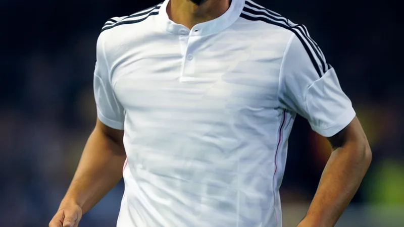 Sami Khedira de retour au Real Madrid dans le staff de José Mourinho Sami Khedira en costume, souriant, à côté de José Mourinho dans un stade de football, avec le logo du Real Madrid en arrière-plan.