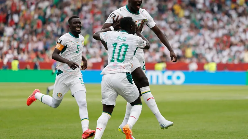 Joueurs sénégalais célébrant un but lors du match Sénégal-Irak au stade de Toronto, avec le maillot vert et le drapeau sénégalais agité par les