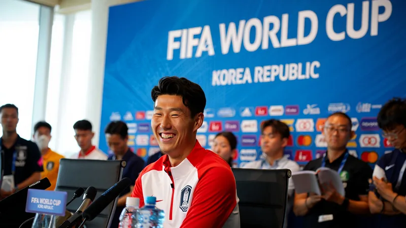 Son Heung-min : l'icône sud-coréenne qui dépasse les statistiques Son Heung-min en tenue de l'équipe nationale sud-coréenne, souriant et levant le pouce, devant un stade de football rempli de supporters agitant des