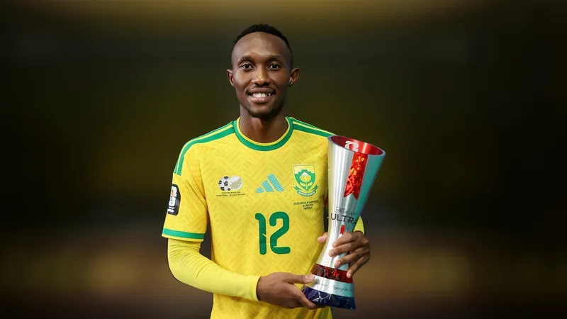 Thapelo Maseko, joueur sud-africain en tenue des Bafana Bafana, célébrant après un match sur une pelouse avec des supporters en arrière-plan.