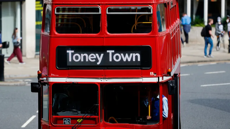 Un bus rouge à impériale de Stagecoach Midlands avec l'écriteau « Toney Town » traversant une rue de Northampton, devant le Sixfields Stadium.