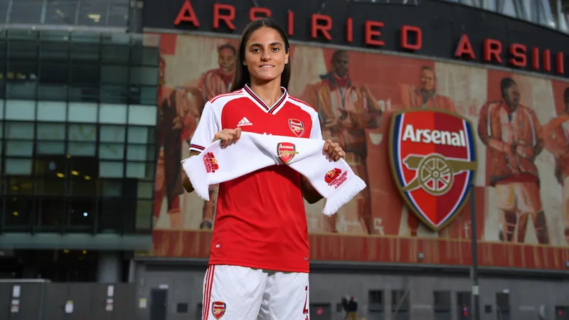 Arsenal recrute la milieu suisse Reuteler — Football World Cup News Geraldine Reuteler en tenue d'Arsenal, souriante, posant avec un maillot numéro 14 devant le logo du club à Londres. — latest news and analysis.