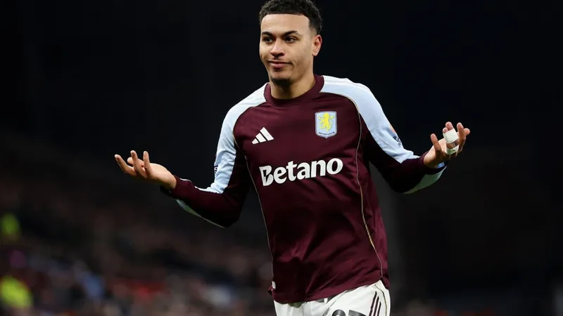 Un joueur d'Aston Villa dribblant sur l'aile lors d'un match de Premier League, avec le maillot violet et le logo du club visible.