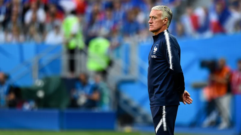 Didier Deschamps, sélectionneur de l'équipe de France, regarde le match depuis le bord du terrain, vêtu d'un costume sombre, avec une expression