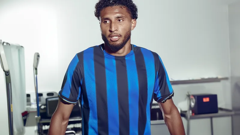Un joueur de football brésilien en tenue de l'Atalanta, souriant, sur un terrain vert avec un stade en arrière-plan. — latest news and analysis.