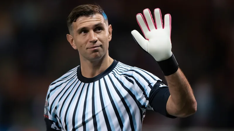 Juventus propose un premier contrat à Dibu Martínez — Football World Emiliano 'Dibu' Martínez en tenue de gardien d'Aston Villa, concentré sur un match de Premier League, avec le logo de la Juventus en arrière-plan.