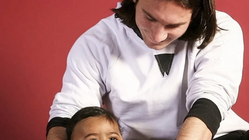 Leo Messi : « Cette photo avec Lamine… c'est juste fou ! » — Football Lionel Messi souriant, tenant un ballon de football, avec une photo encadrée de lui et d'un bébé Lamine Yamal en arrière-plan