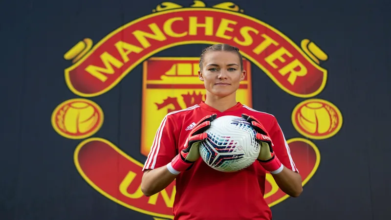 Janina Leitzig signe à Manchester United — Football World Cup News Janina Leitzig en tenue de gardienne de but, souriant devant le logo de Manchester United lors de sa présentation officielle.