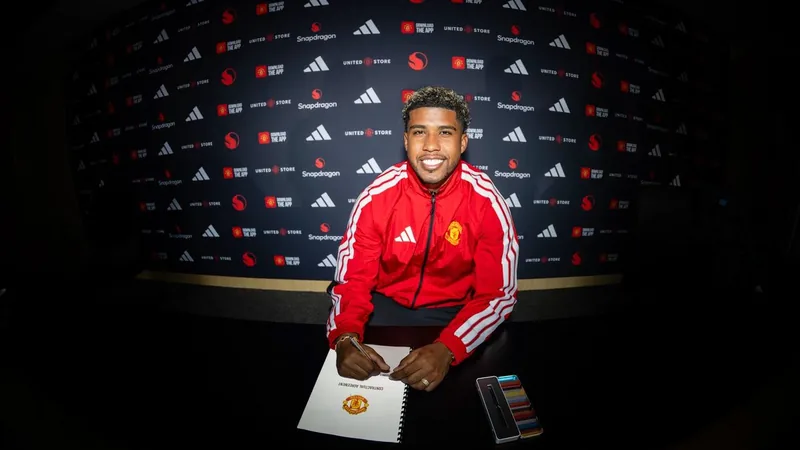 Andrey Santos en tenue de Manchester United, souriant, tenant un maillot rouge devant le logo du club à Old Trafford. — latest news and analysis.