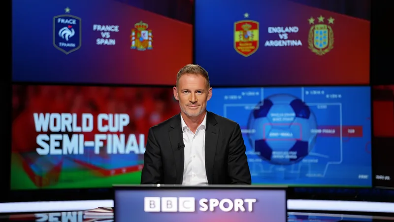 Prédictions de Chris Sutton pour les demi-finales de la Coupe du Chris Sutton souriant devant un micro de BBC Sport, avec un fond de stade de football et un ballon de la Coupe du Monde 2026.